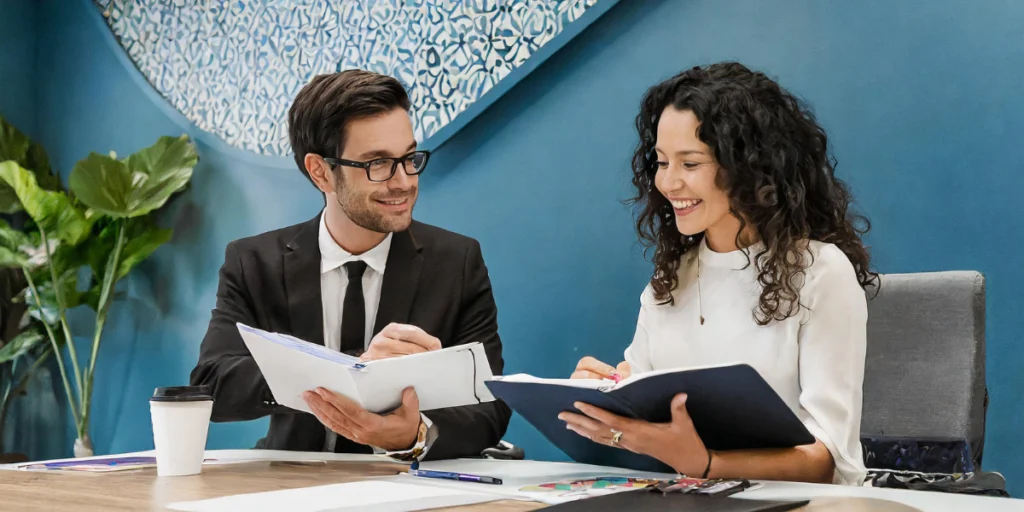 O que é benchmarking e por que é essencial para sua empresa- mulher e homem conversando com cadernos nas maos