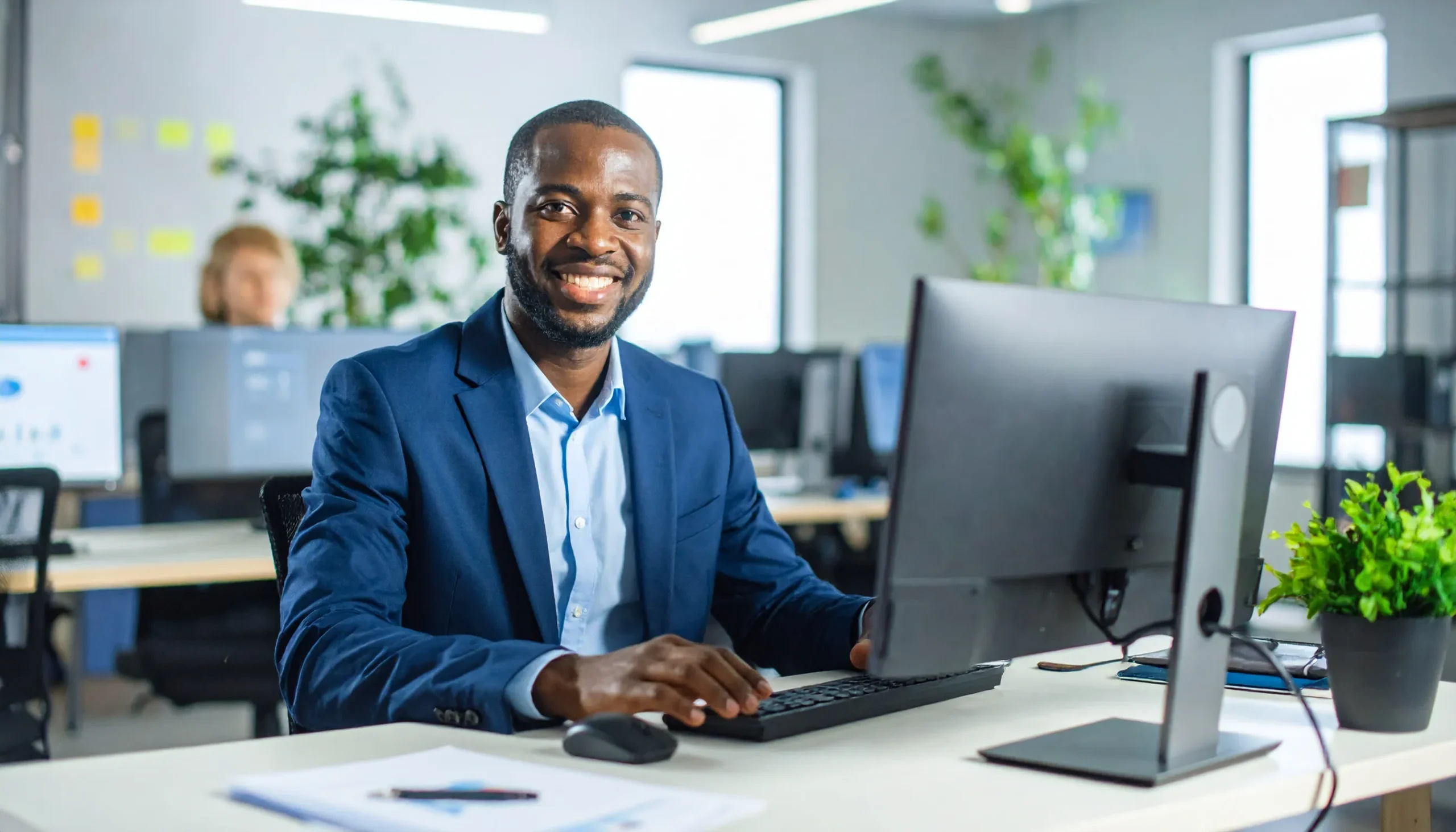 um-profissional-mexendo-no-computador-em-um-escritorio-de-dia-com-plantas-na-mesa - Monitoramento de mídia em tempo real com Knewin Monitoring